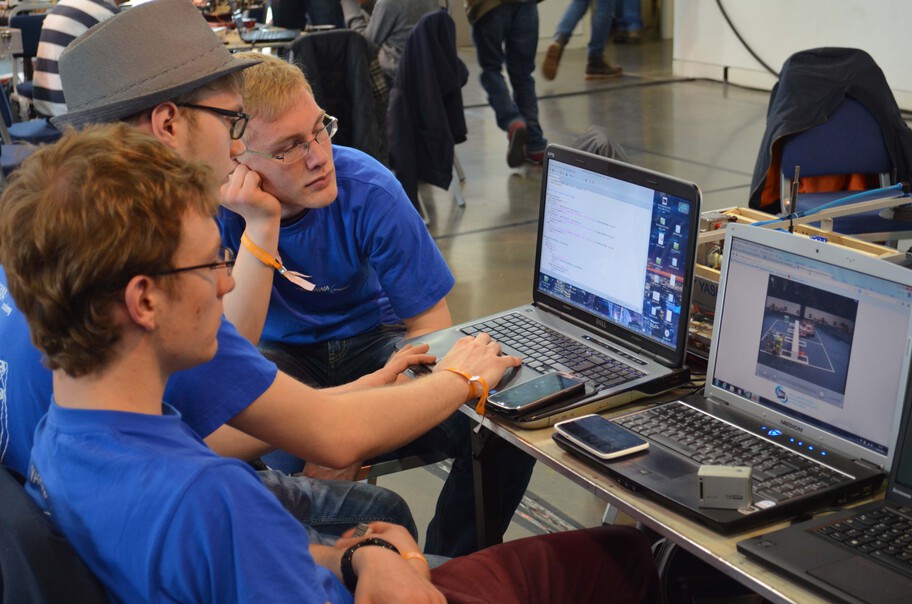 Three competitors sitting in front of a laptop