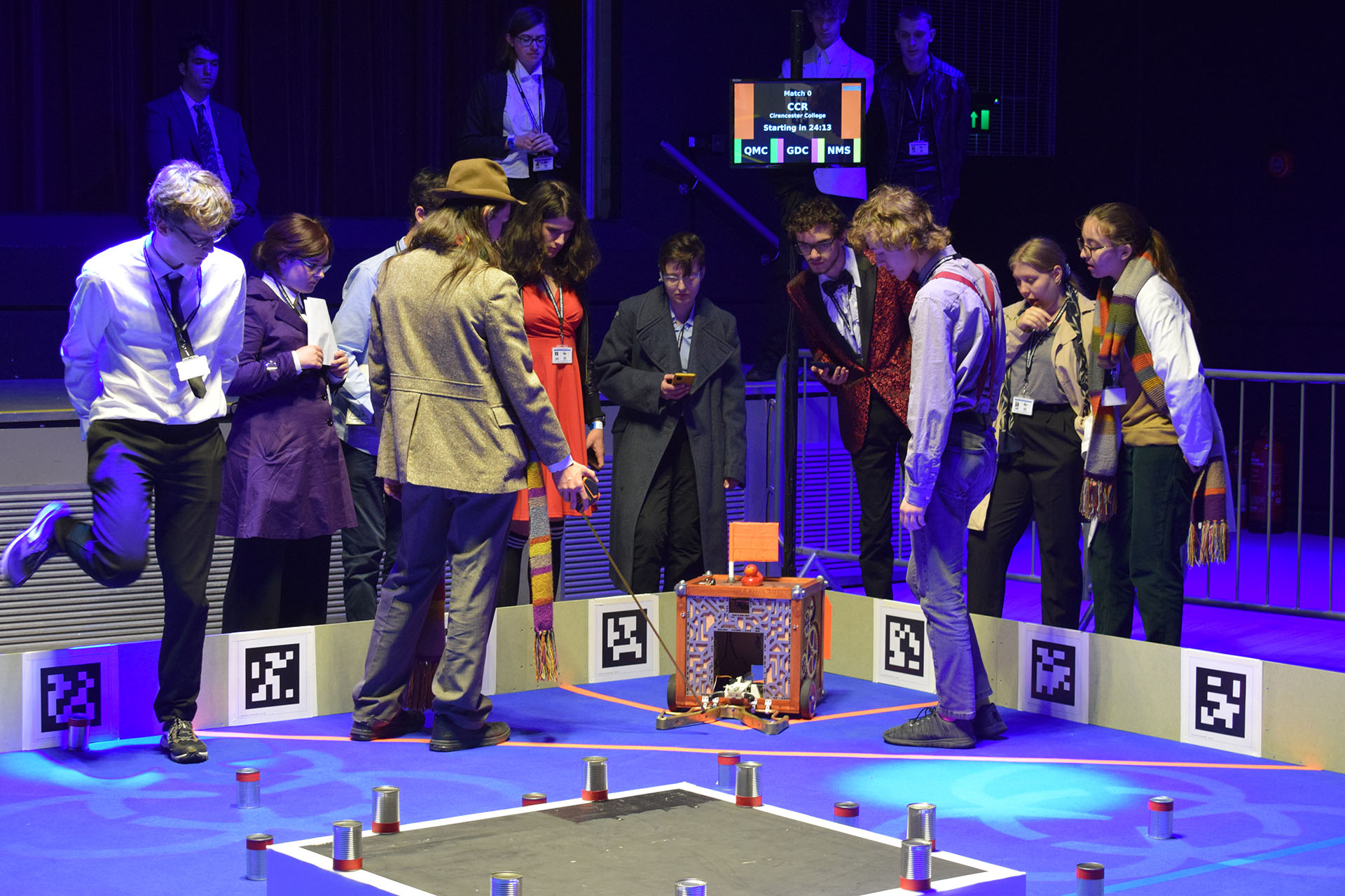 The
           competitors from Hills Road Sixth Form College dressed up as Doctor
           Who Characters standing in the arena looking at their robot